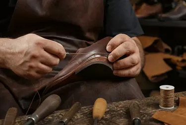 Sapateiro utilizando máquina de costura para reparar calçado.
